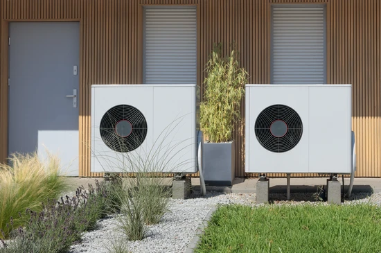 Extérieur résidentiel moderne avec deux pompes à chaleur air-eau blanches installées sur dalles béton