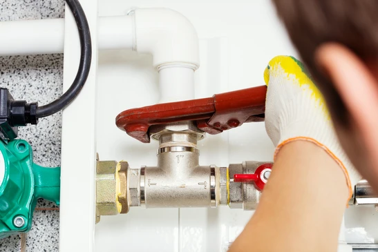 Plombier professionnel en gants jaunes installant une vanne d'arrêt sur canalisation