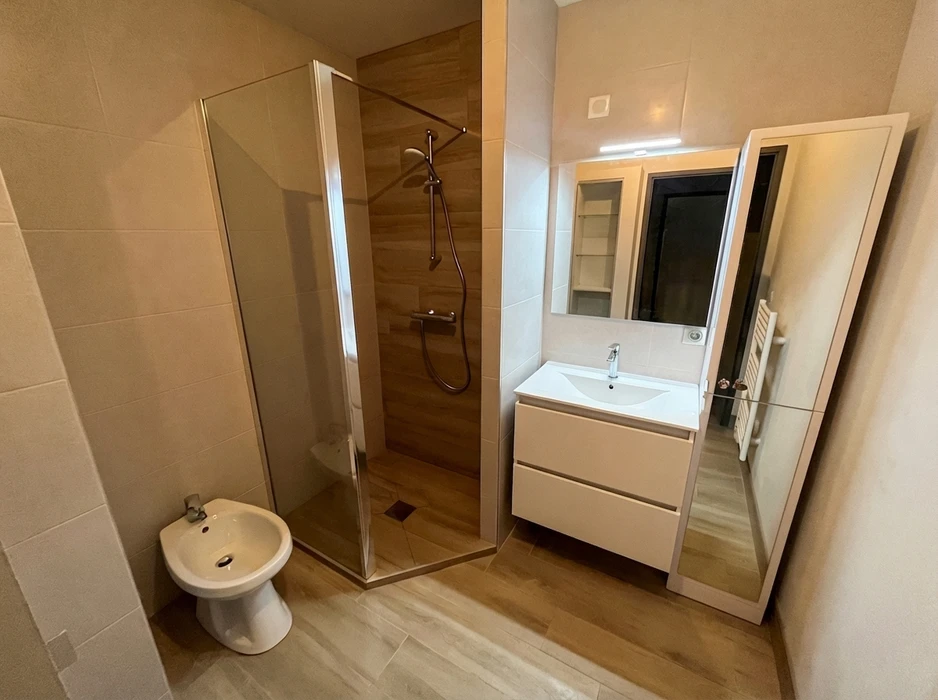 Salle de bain moderne rénovée avec douche à l'italienne en verre transparent, parois carrelées imitation bois
