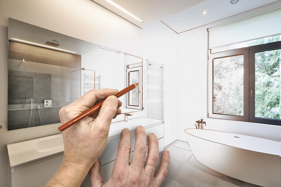 Deux artisans en combinaisons noires et t-shirts orange installent un meuble dans une salle de bain moderne aux murs en marbre blanc
