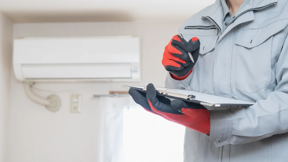 Technicien HVAC en uniforme vert travaillant sur système de chauffage/climatisation dans intérieur résidentiel