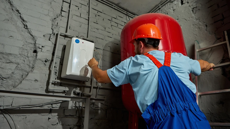 Plombier professionnel en uniforme travaillant dans une salle de bain moderne blanche